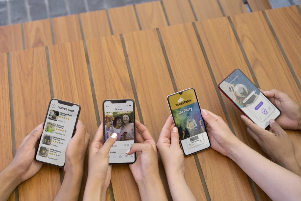 Hands holding four mobile phones with different campaigns on each, showing our effective strategy in social media marketing agency services.