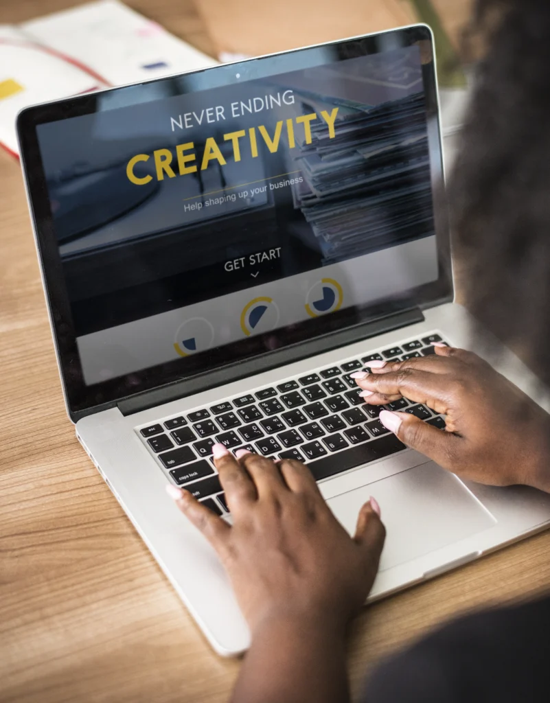 A GrowEasy web developer, part of the Best Digital Marketing Agency in Haldwani, designing a website on a laptop with "Never Ending Creativity" displayed on screen.